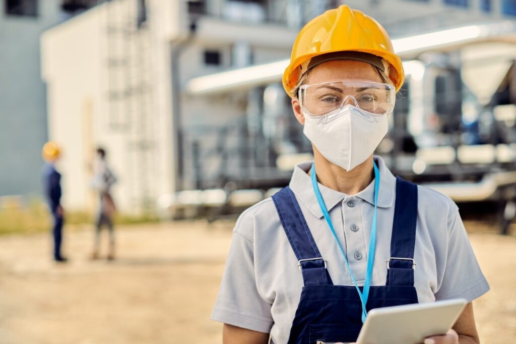 female building contractor with digital tablet wearing face mask at construction site